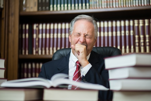 Mężczyzna czyta nudną książkę w jego pracownianej bibliotece