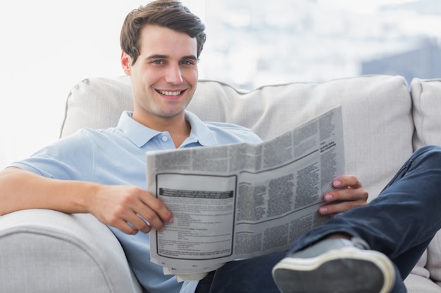 Mężczyzna czytający gazetę siedział na kanapie
