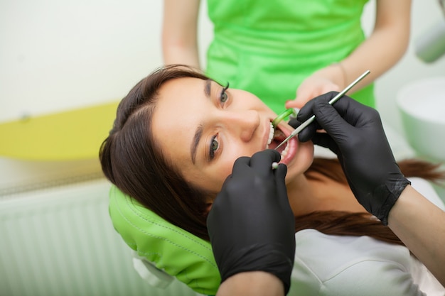 Mężczyzna dentysta leczy zęby klientowi w klinice dentystycznej