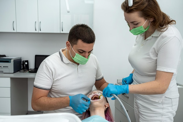 mężczyzna dentysta prowadzi leczenie z asystentem do zadowolonej klientki gabinetu dentystycznego ludzie rozmawiają i patrzą na siebie ludzie medycyna