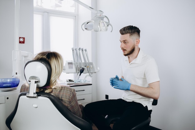 Mężczyzna dentysta za pomocą cyfrowego tabletu i rozmawia z pacjentem w klinice dentystycznej