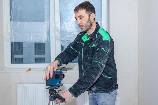 Mężczyzna dokonuje napraw w nowych mieszkaniach Builder poziomuje ściany za pomocą poziomu lasera