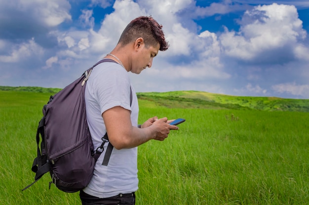 Mężczyzna dzwoniący przez telefon komórkowy, młody człowiek w polu dzwoniący przez telefon komórkowy, młody turysta z telefonem komórkowym w polu i kopia przestrzeń