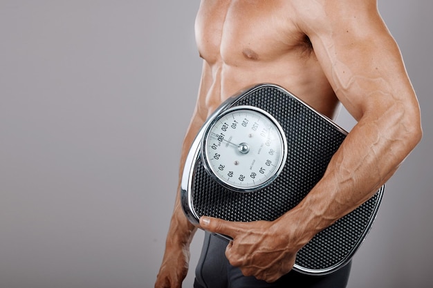 Mężczyzna fitness i skala diety odżywiania ciała i reklama ćwiczeń odchudzających Schudnij i ćwicz model stylu życia z mięśniami na szarej makiecie studyjnej do marketingu zdrowotnego