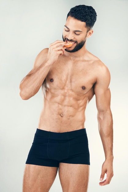 Zdjęcie mężczyzna fitness zdrowotny i zdrowa dieta podczas jedzenia pomarańczy dla odżywiania i dobrego samopoczucia witaminą c z dopasowanym uśmiechem i bielizną model sportowca z owocami dla energii i korzyści związanych z samoopieką