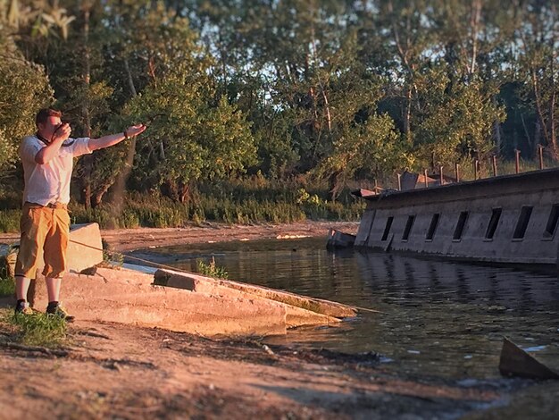 Zdjęcie mężczyzna fotografuje przez kamerę, stojąc na brzegu jeziora