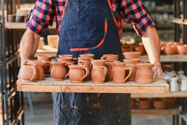 Mężczyzna Garncarza Ręce Trzyma Tacę Z Pieczonymi Garnkami Ceramicznymi W Ceramice.