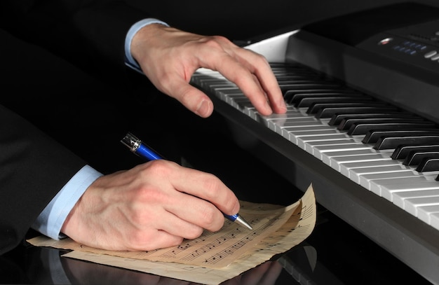 Mężczyzna gra na pianinie i pisze na parerze dla notatek