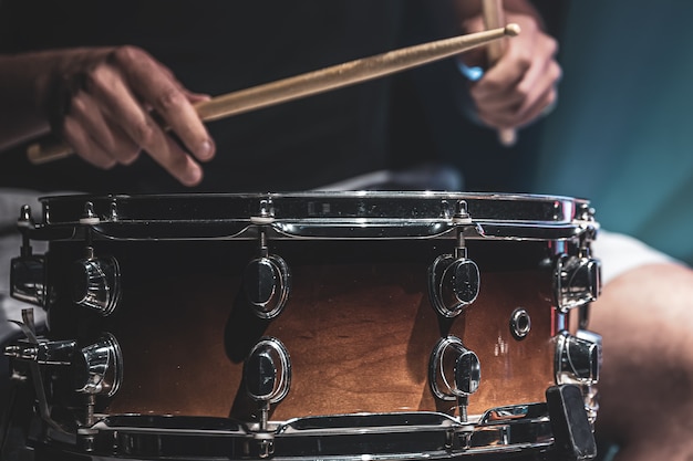 Mężczyzna gra pałkami na bębnie, perkusista gra na instrumencie perkusyjnym, zbliżenie.