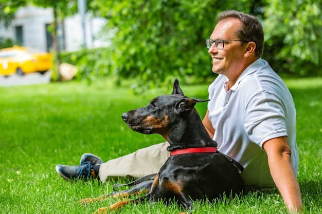 Mężczyzna gra w parku z Dobermannem