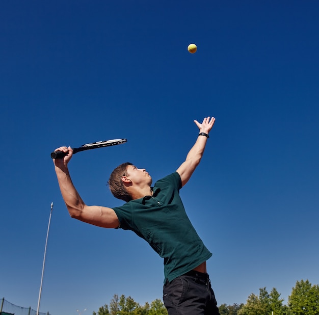 Mężczyzna gra w tenisa na korcie w piękny słoneczny dzień