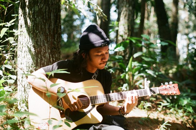 Mężczyzna grający na gitarze w lesie