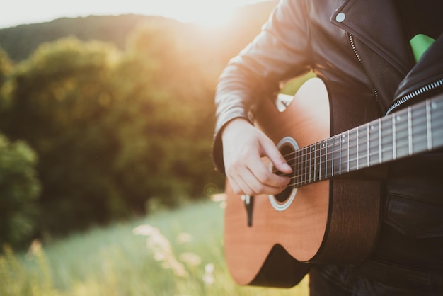 Mężczyzna grający na gitarze w przyrodzie w słoneczny dzień