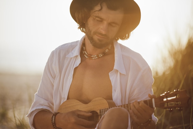 Mężczyzna Grający Na Ukulele Podczas Letnich Wakacji Na Plaży W Pobliżu Morza