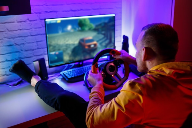 Mężczyzna grający w gry wyścigowe na komputerze Używa kierownicy Gra emocjonalna