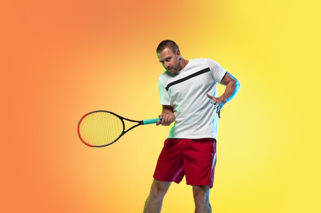 Mężczyzna grający w tenisa na białym tle na studio w świetle neonowym