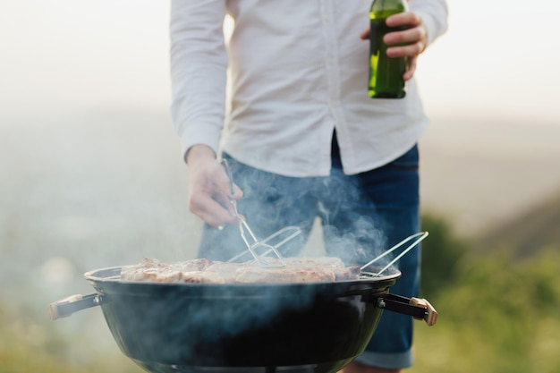 Zdjęcie mężczyzna grillujący mięso podczas picia piwa