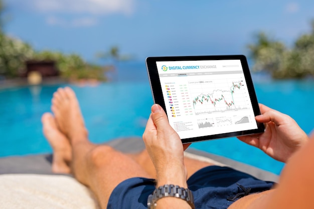 Zdjęcie mężczyzna handlujący cyfrowymi walutami online, relaksując się przy basenie