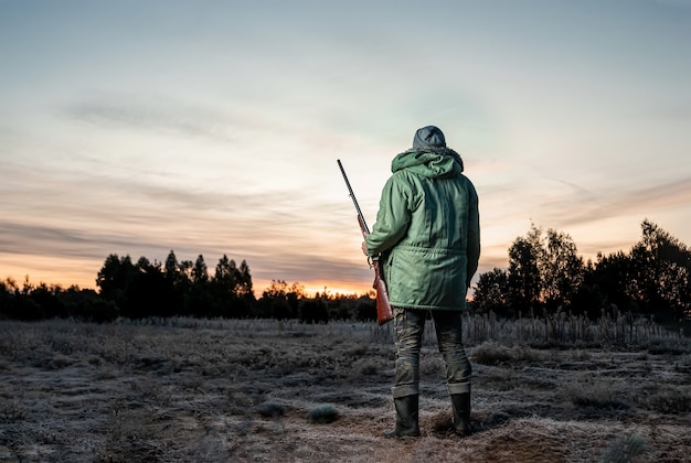 Mężczyzna Hunter w kamuflażu z pistoletem podczas polowania