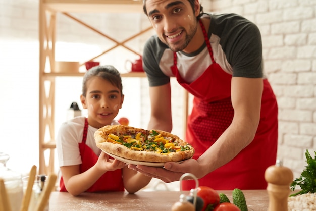 Mężczyzna i dziewczyna gotowane piękna pizza w kuchni.