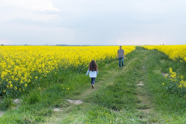 Mężczyzna i dziewczyna idą przez pole kwiatów.