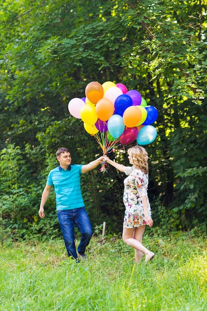 Mężczyzna i jego ciężarna żona z balonami na zewnątrz