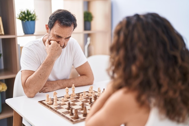 Mężczyzna i kobieta gra w szachy, siedząc na stole w domu
