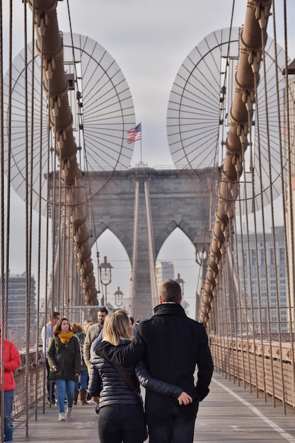 Zdjęcie mężczyzna i kobieta idący po mostku brooklyn w mieście