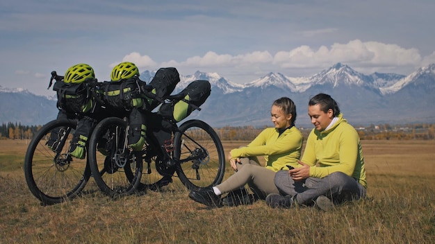 Mężczyzna I Kobieta Jeżdżą Na Rowerze W Terenie Mieszanym Z Bikepackingiem. Podróż W Dwie Osoby Z Torbami Rowerowymi. Pokryte śniegiem Góry.