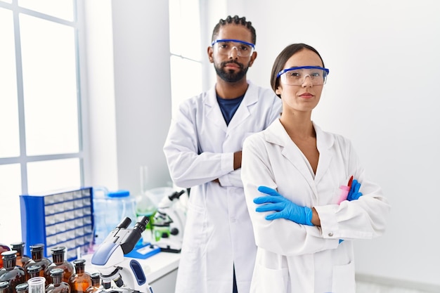 Mężczyzna i kobieta naukowiec partnerzy stojący z rękami skrzyżowanymi gestem w laboratorium