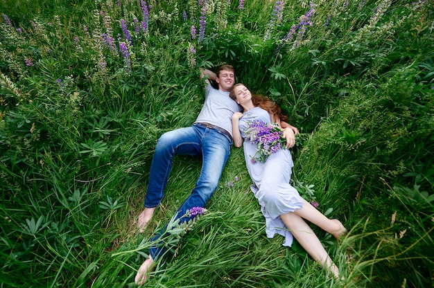 Mężczyzna i kobieta obejmującego leżącego w trawie