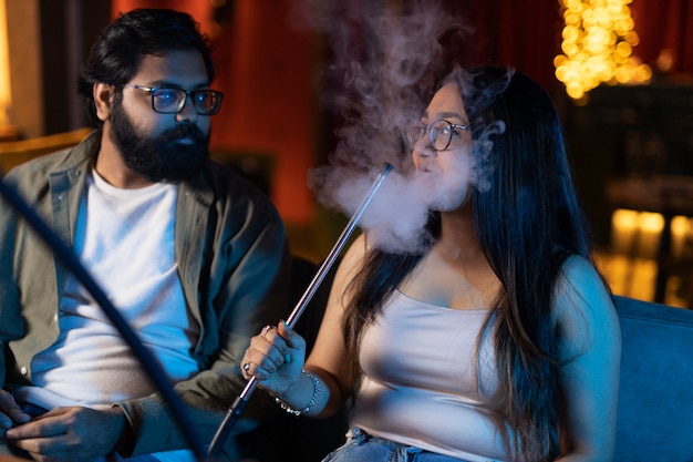 Zdjęcie mężczyzna i kobieta odpoczywają vaping z fajki wodnej w barze