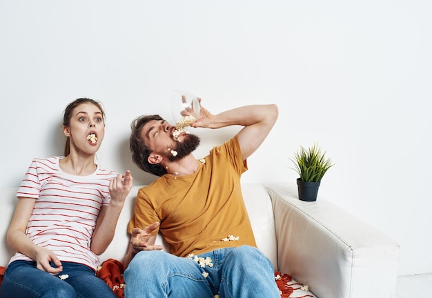 Mężczyzna i kobieta oglądają filmy w pomieszczeniu z popcornem i kwiatem w garnku