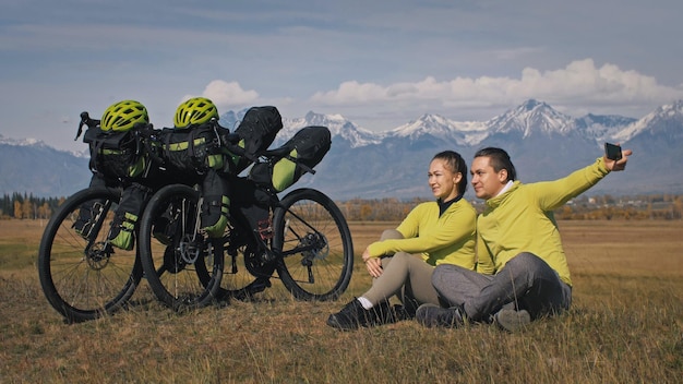 Mężczyzna i kobieta podróżują po mieszanym terenie rowerowe wycieczki rowerowe z bikepackingiem w dwie osoby podróżują z torbami rowerowymi Sport bikepacking rowerowa odzież sportowa w zielono-czarnej kolorystyce Górski śnieg pokryty