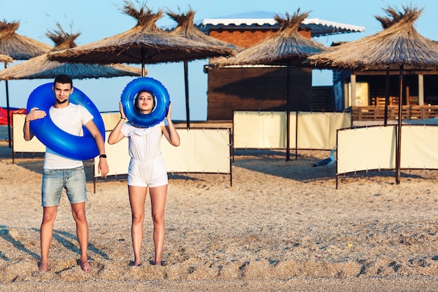 Mężczyzna i kobieta pozują na plaży i trzymają nadmuchiwane koła. koncepcja letnich wakacji na morzu.