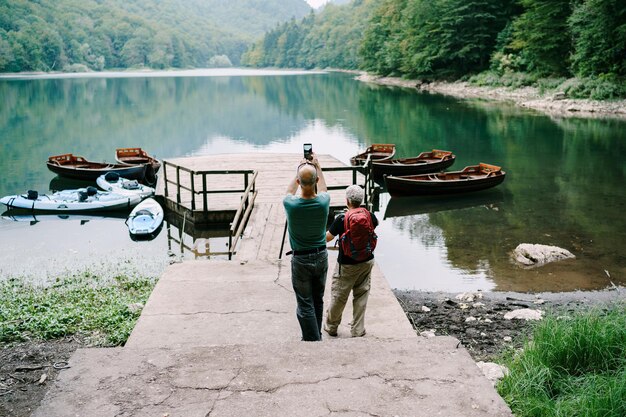 Mężczyzna i kobieta robią zdjęcia łodzi na molo nad jeziorem lago di braies włochy