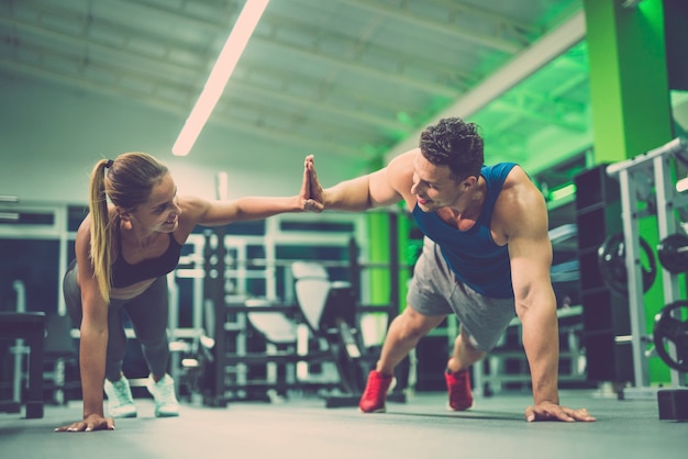 Mężczyzna i kobieta robiący ćwiczenia push up i gesty na siłowni