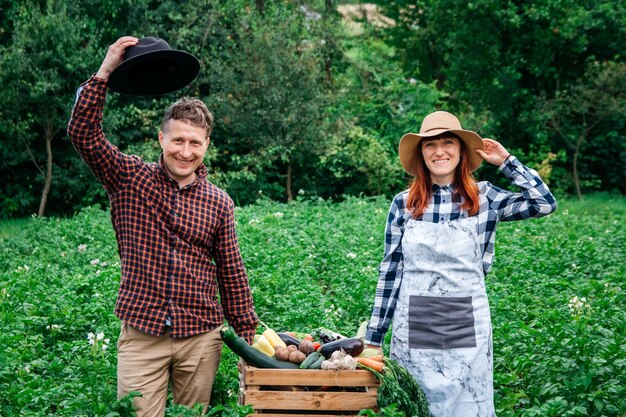 Mężczyzna I Kobieta Rolnicy W Kapeluszach Trzymający świeże Organiczne Warzywa W Drewnianym Pudełku