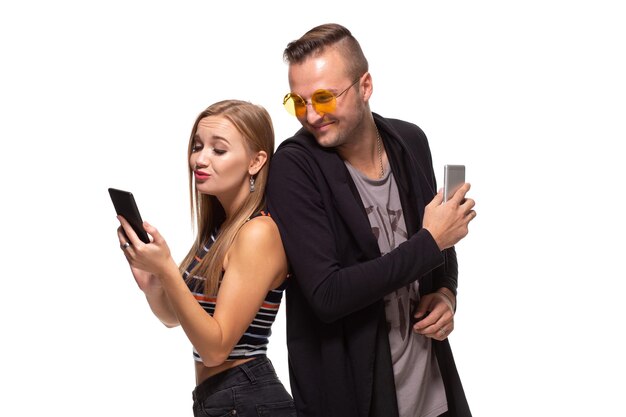 Mężczyzna i kobieta stoją plecami do siebie z telefonami w rękach na białym tle