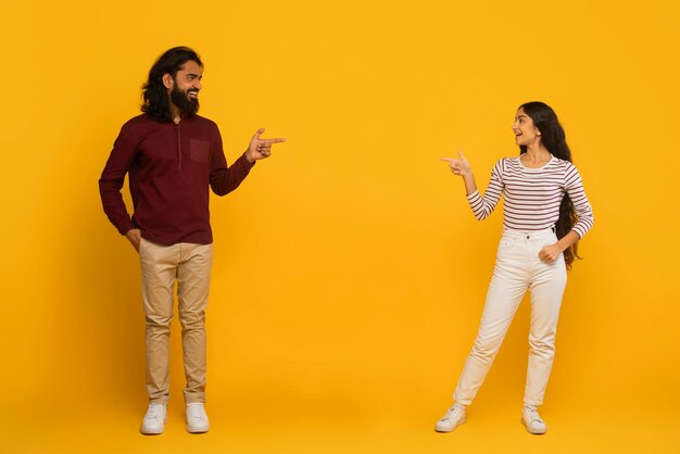 Mężczyzna i kobieta wskazują na siebie na żółtym tle