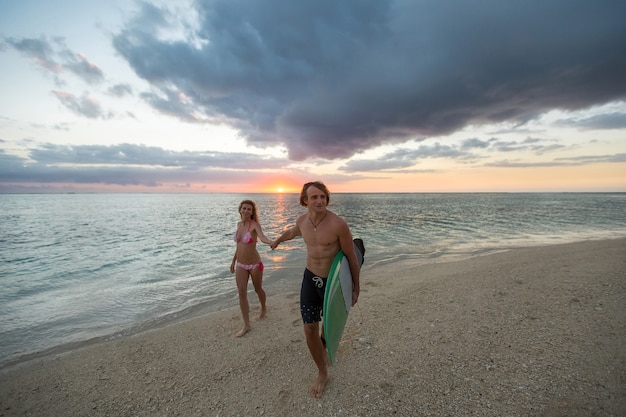 Mężczyzna i kobieta z deskami surfingowymi o zachodzie słońca