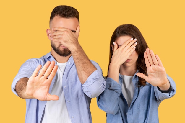 Mężczyzna i kobieta zakrywający oczy pokazujący gest zatrzymania ręki