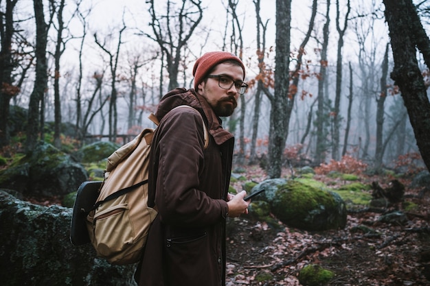 Zdjęcie mężczyzna idący na ciemnej ścieżce przez upiorny las. hipster z plecakiem za plecami wyrusza na wycieczkę