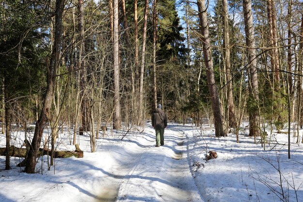 Mężczyzna idzie zaśnieżoną leśną drogą