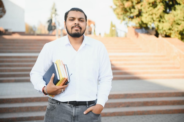Mężczyzna indyjski student stojący na uniwersytecie z książką