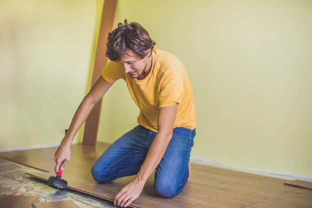 Mężczyzna instalujący nowe drewniane podłogi laminowane. ogrzewanie podłogowe na podczerwień pod podłogą laminowaną