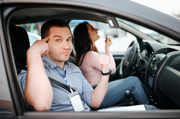 Mężczyzna instruktor auto przystępuje do egzaminu u młodej kobiety