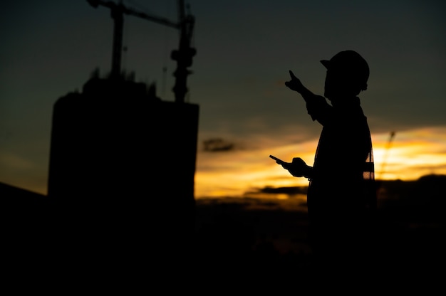 mężczyzna inżynier pracujący na budowie w Silhouette Sunset time