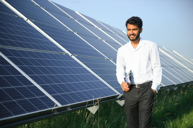 Mężczyzna inżynier sprawdza fotowoltaiczną elektrownię słoneczną i używa tabletu nagrywającego Indianin w mundurze trzymający tablet