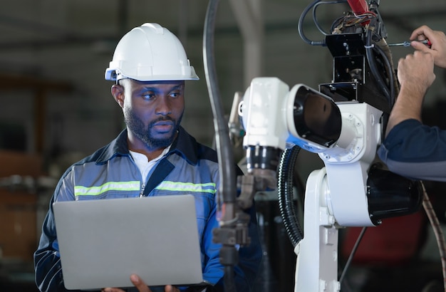 mężczyzna inżynier sprawdzający i kontrolujący kontrolę spawarki ramienia robota z laptopem w fabryce